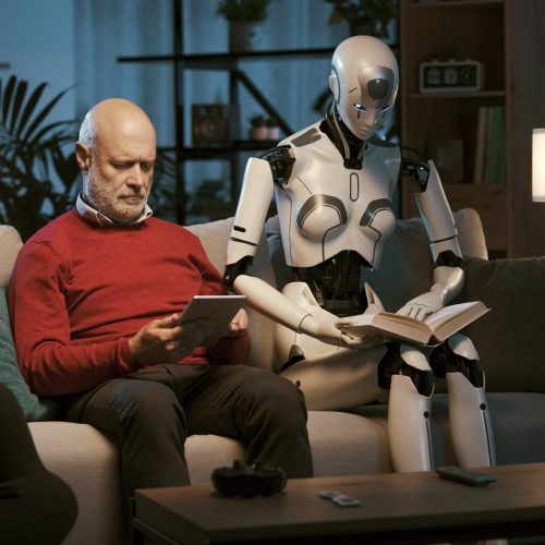 Humanoid AI robot and senior man sitting on the couch and spending time together: the man is using a tablet and the robot is reading a book